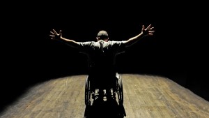 Uomo in sedia a rotelle sul palco di un teatro