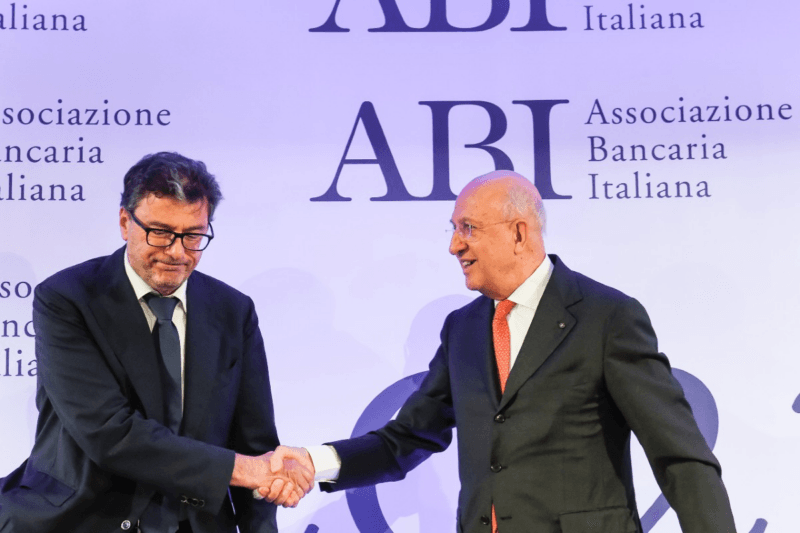 Tassa sugli extraprofitti, in realtà è un regalo alle banche: il ministro dell'Economia Giorgetti stringe la mano con rassegnazione al presidente ABI Patuelli