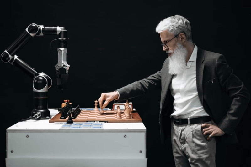 Intelligenza artificiale e ricchezza redistribuita: un uomo gioca a scacchi contro un braccio robotico