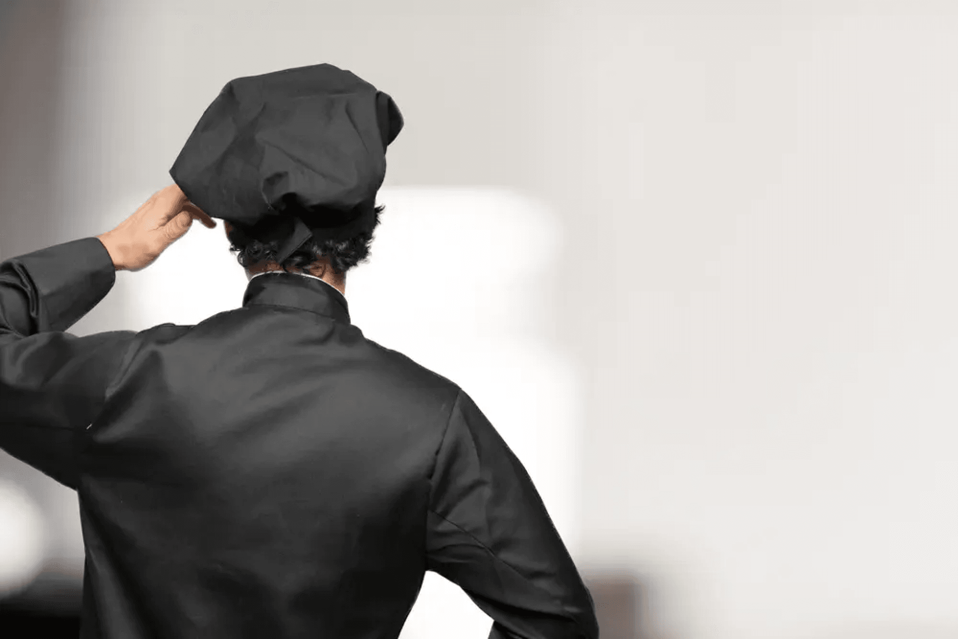 Cuochi e camerieri non si trovano: uno chef vestito di nero, di spalle