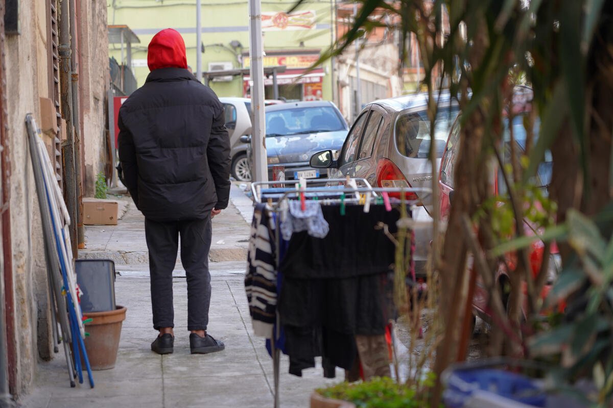 Lavoro minorile in Italia: un ragazzo di spalle, per strada, vicino a dei panni stesi