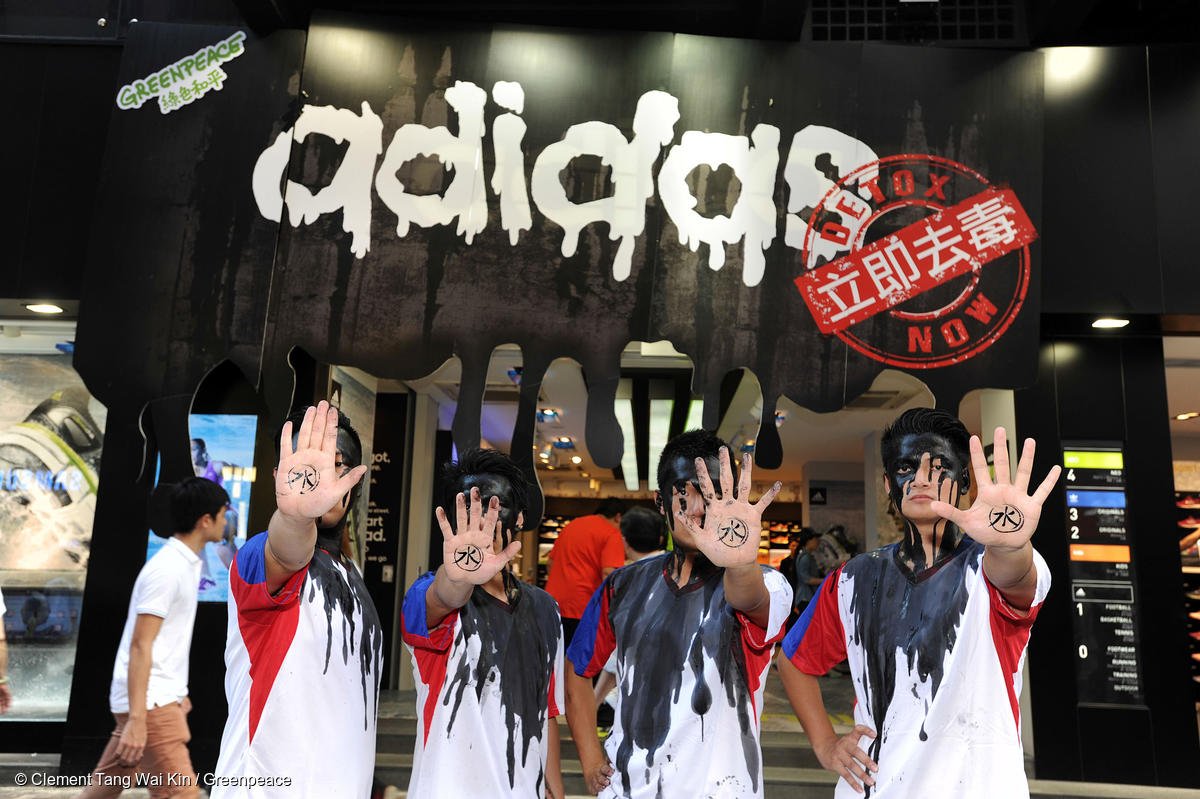 Salari della moda, degli attivisti fanno cenno di stop con la mano in una vetrina griffata Adidas