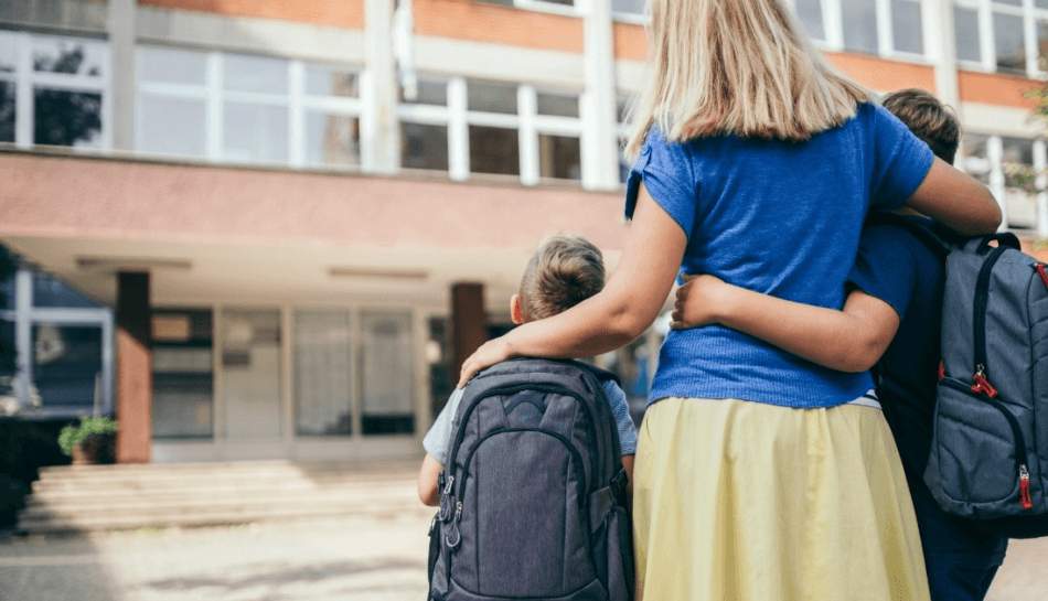 Genitori invadenti: una madre abbraccia i figli davanti all'ingresso della scuola