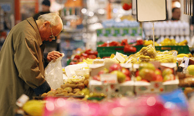 Patto salva-spesa: un anziano seleziona accuratamente la frutta al supermercato