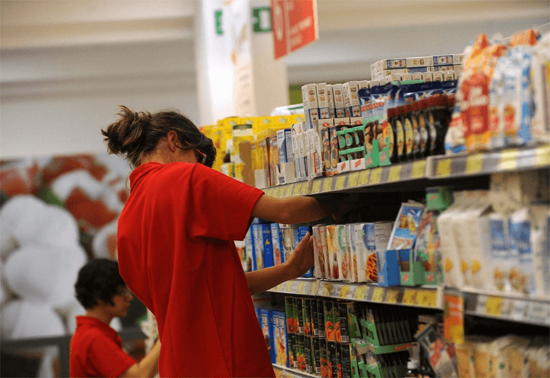 Scaffalisti all'opera: due scaffaliste collocano prodotti nella corsia di un supermercato