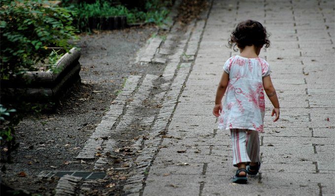 Sempre più minori in povertà assoluta nel 2023: una bambina cammina da sola su una strada scalcinata