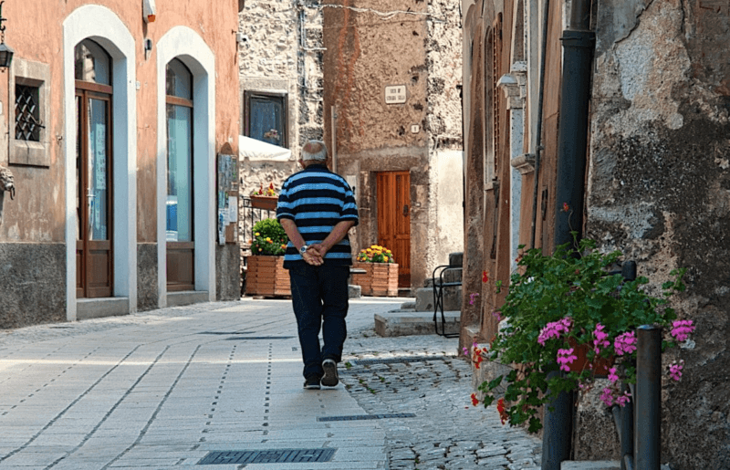 Calo demografico, un uomo anziano cammina solo per un paesino del Sud Italia