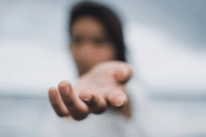 La mano tesa di un'educatrice davanti a un volto sfocato