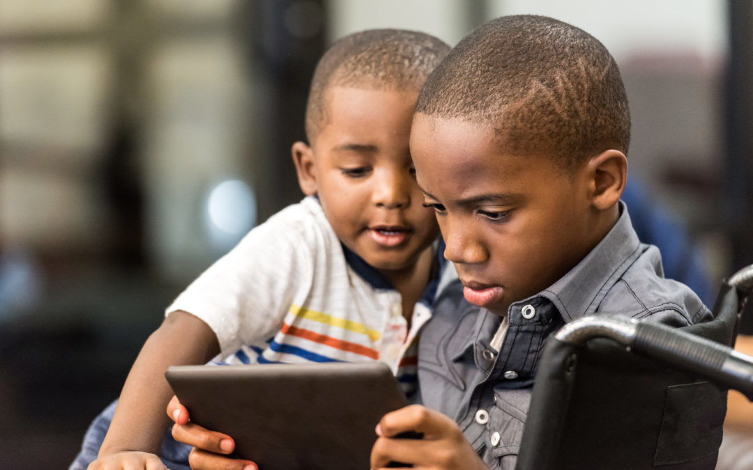 Due bambini immigrati guardano un tablet: immagine di migrazione digitale