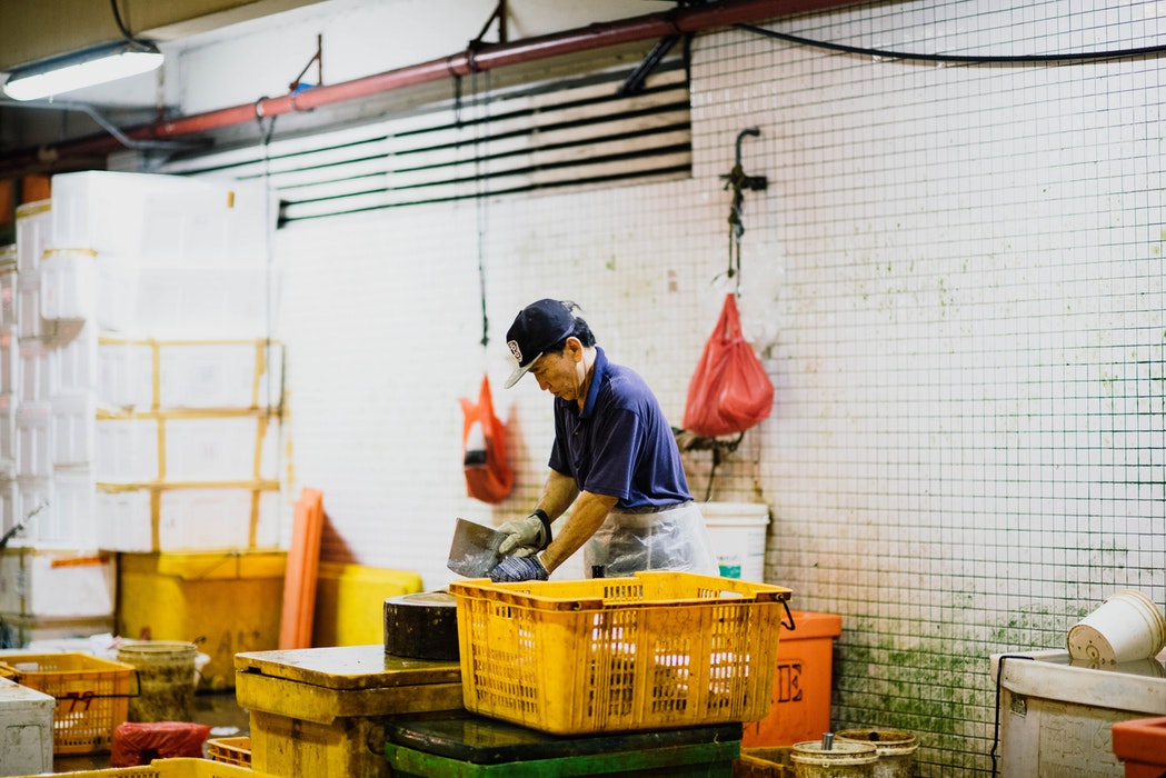 esempio di intraprendenza dei lavoratori stranieri: uomo orientale lavora del pesce