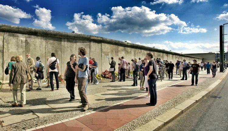 Uomini e donne di fronte a un confine delimitato da un muro.