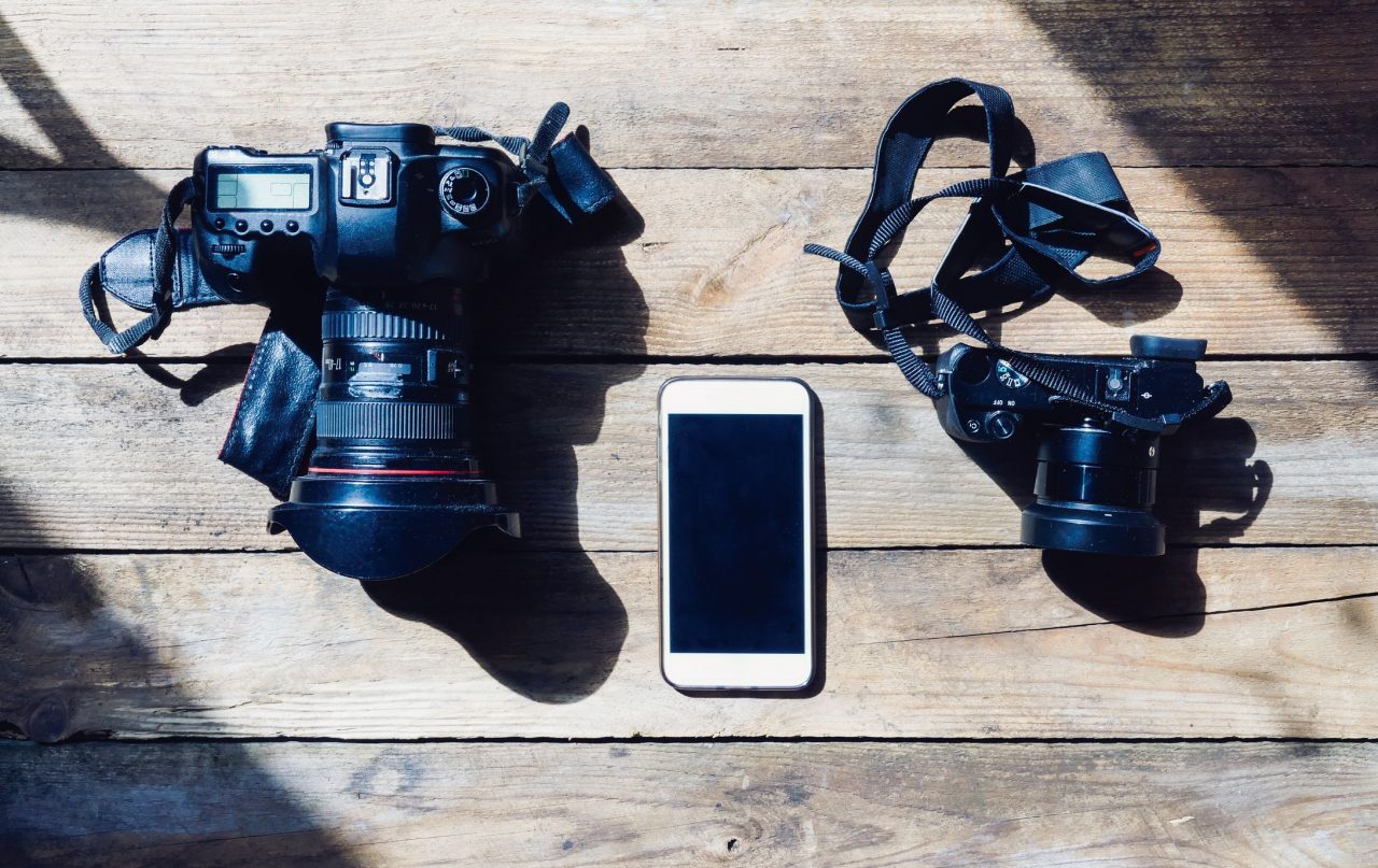 La crisi dell'audiovisivo rappresentata da una macchina fotografica professionale, una amatoriale e uno smartphone l'uno accanto alle altre.