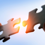 Metafora del lavoro di fusionista: due mani collegano pezzi di un puzzle.