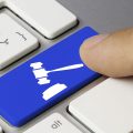 Processi online: un dito su una tastiera preme il tasto per emettere la sentenza