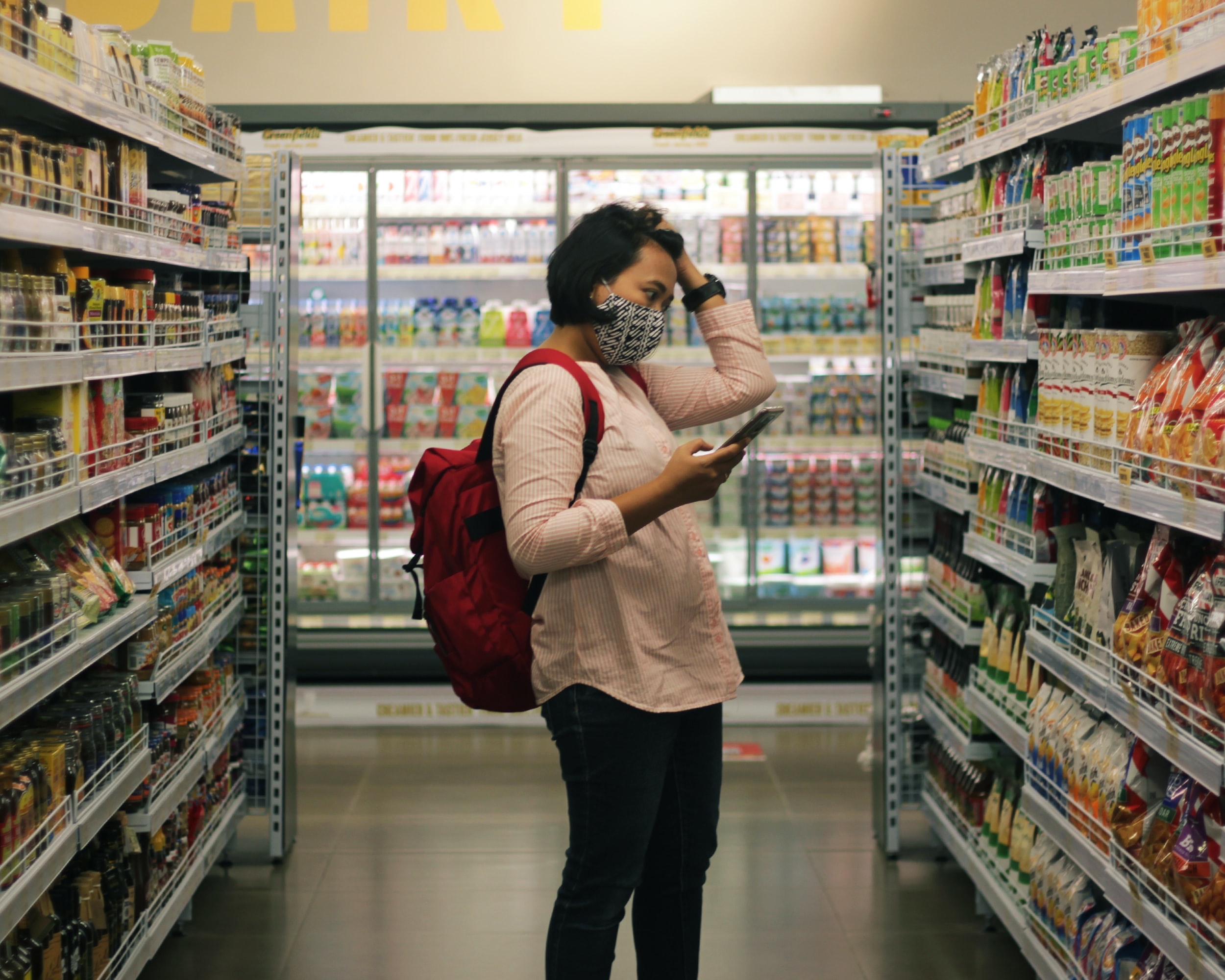 Una consumatrice in supermercato in mezzo a prodotti a Marca del Distributore.