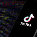 Un cellulare con schermata di TikTok e stringhe dell'algoritmo sullo sfondo.