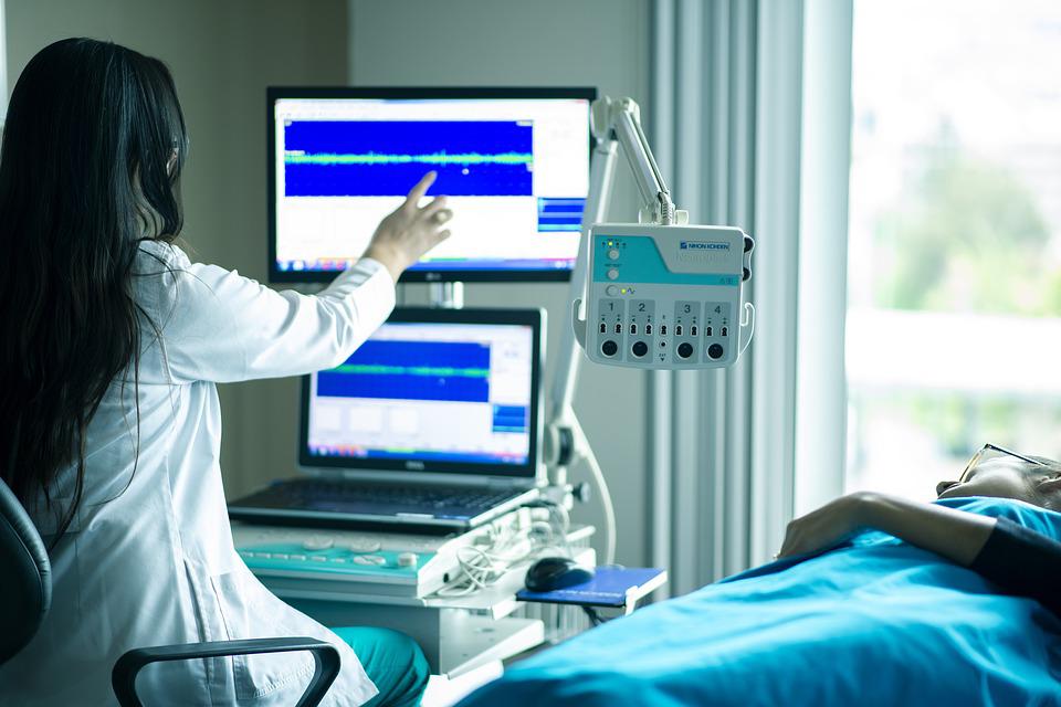 Un'operatrice sanitaria di fronte a uno schermo con un paziente ricoverato.
