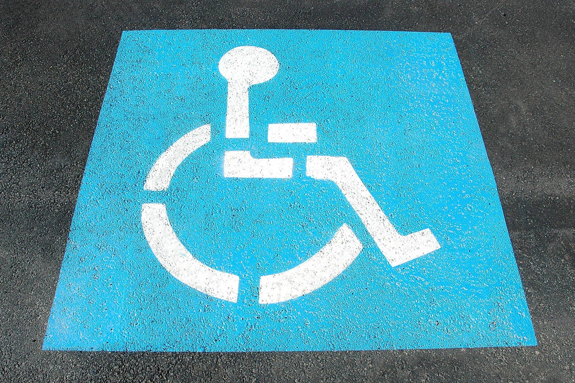 Disabilità e RdC: il simbolo di una carrozzina impresso sull'asfalto.