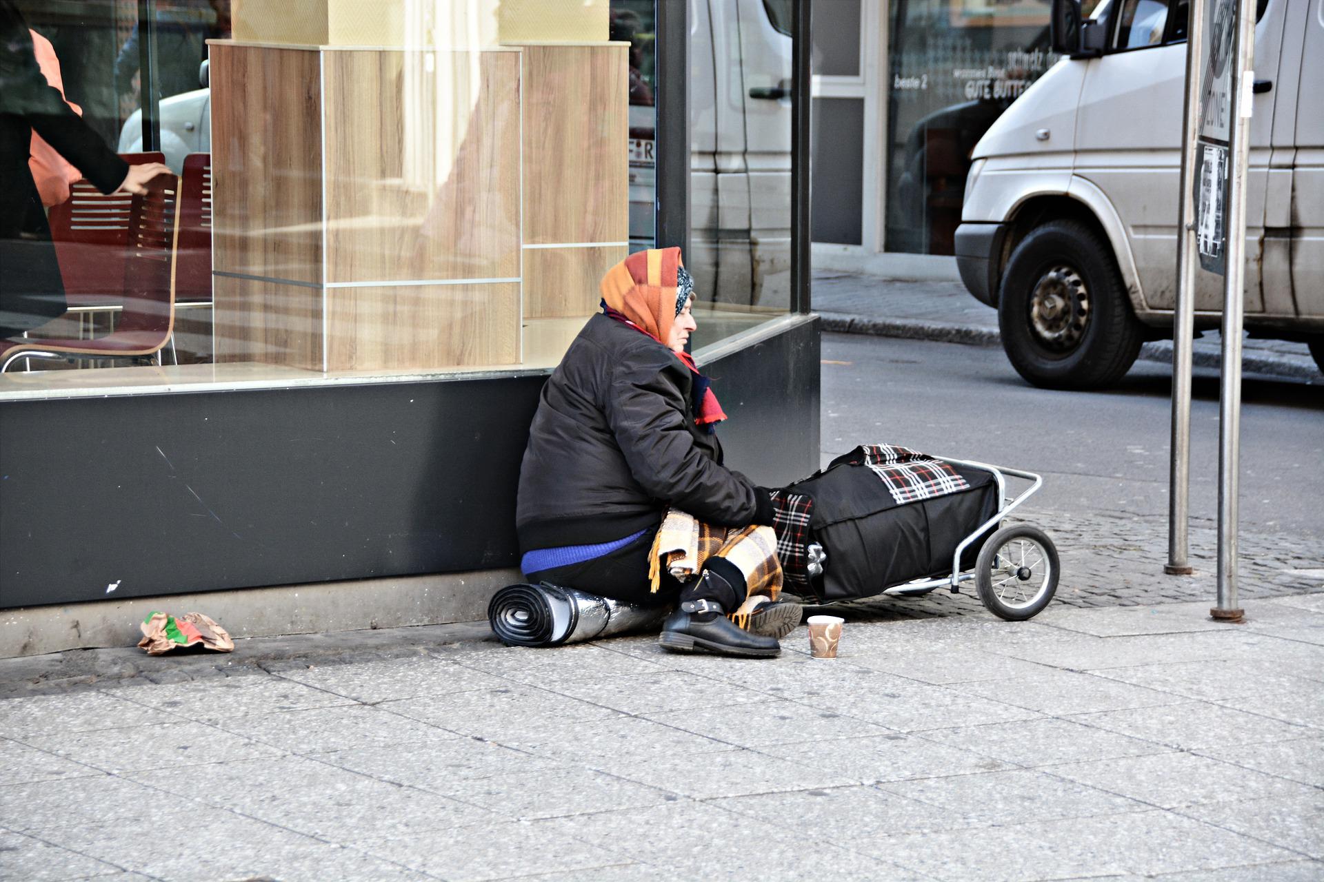 Dal Reddito di inclusione al RdC: una donna in povertà seduta all'angolo della strada.