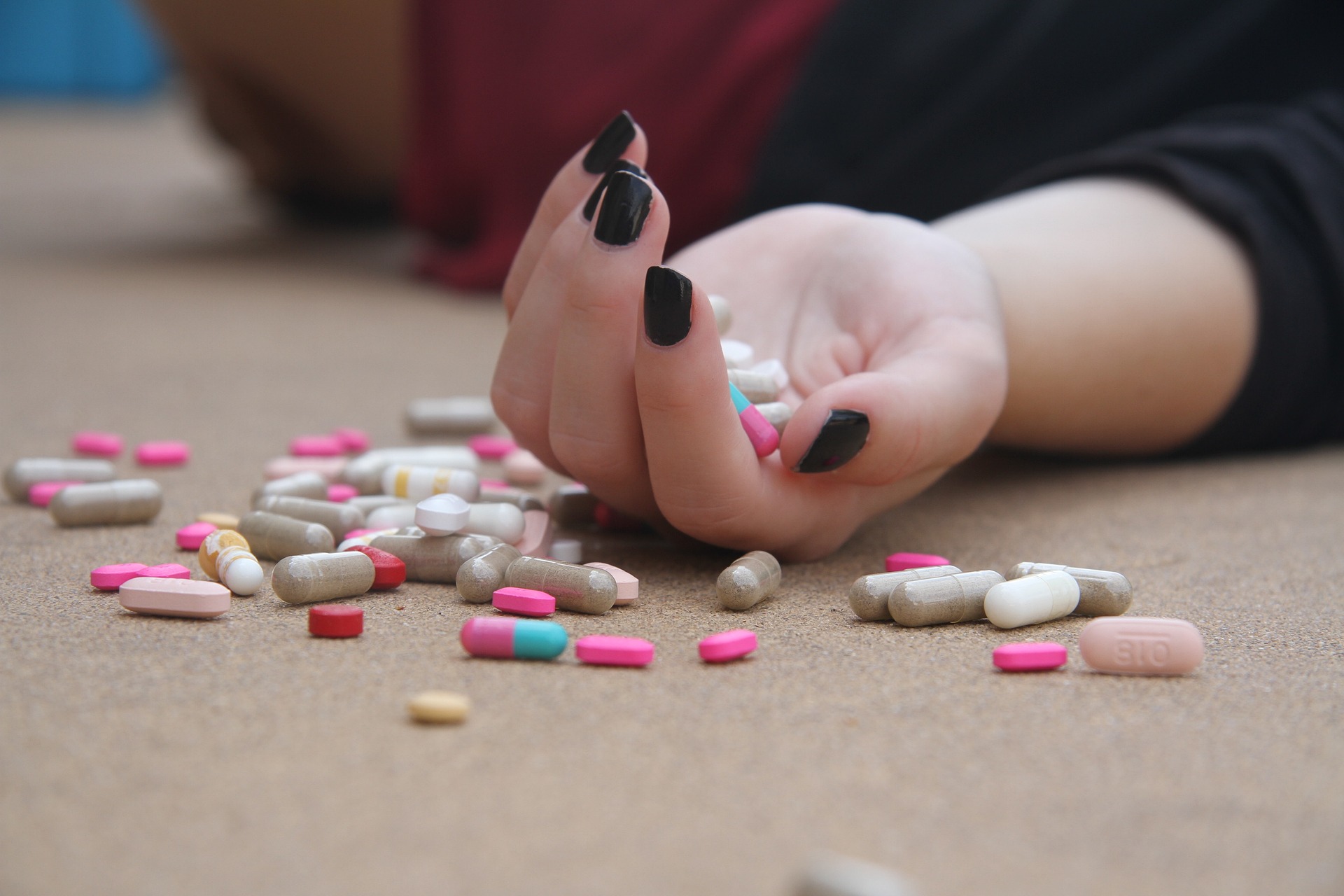 Salute mentale, la mano di una donna svenuta in mezzo a molte pillole.
